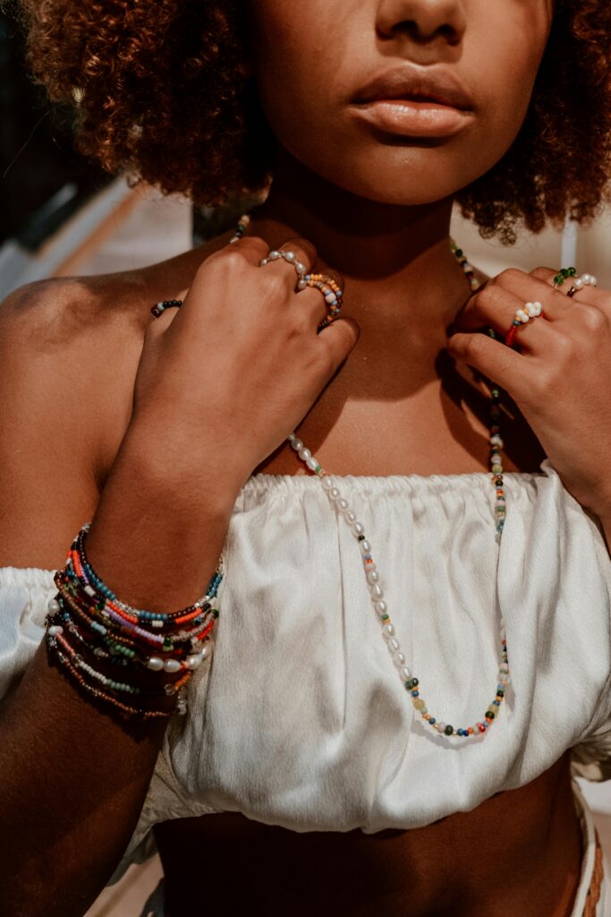 Close-up of a woman with beads and jewelry wearing a white crop top, exuding fashion and elegance.