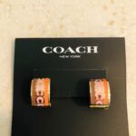 coach signature enamel huggie earrings featuring an animal print pattern and gold tone finish.