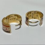 coach signature enamel huggie earrings featuring an animal print pattern and gold tone finish.