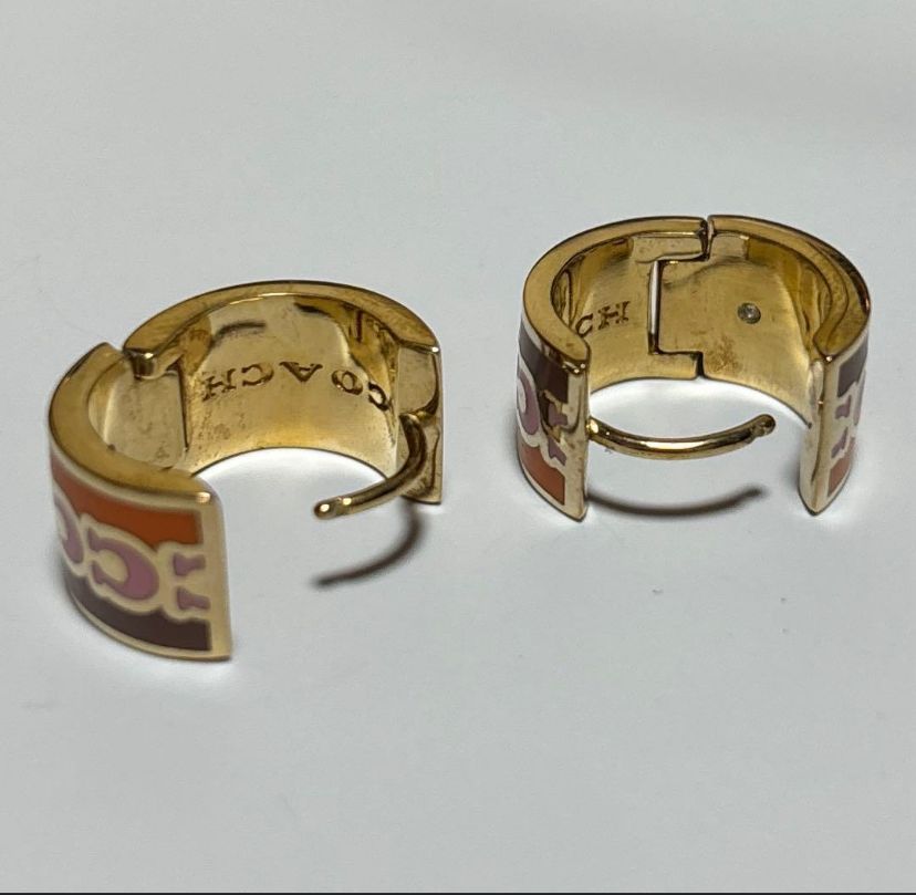 coach signature enamel huggie earrings featuring an animal print pattern and gold tone finish.